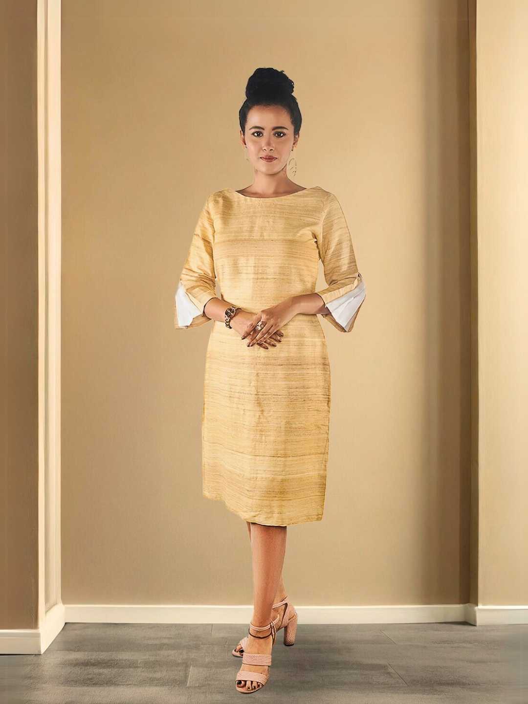 Eila Shift Dress – A beige shift dress crafted in a rich eri silk and tussar blend, the Eila Dress by Jhultaru radiates earthy elegance. Made with 70% eri silk + 30% tussar silk – naturally lustrous, breathable, and responsibly woven.