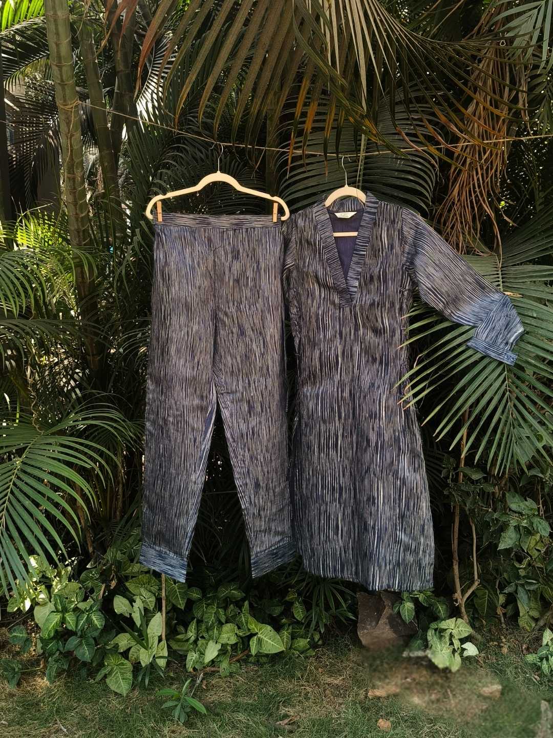 Siona Co-ord Set- Handwoven Tussar Silk | Jhultaru. Fabric: 100% Handwoven Tussar Silk Color: Indigo with tonal striations Top:Deep V-neck with inner contrast panelSide tie-up for adjustable fitFull-length sleeves with cuffs Bottom:Mid-rise straight fitAnkle length with a clean hemElasticated back waist for comfort- Siona Co-ord Set in handwoven tussar silk with natural indigo striations. Includes a V-neck kurta and tapered pants. Elegant. Timeless. Rooted. Sustainable and Eco-friendly.