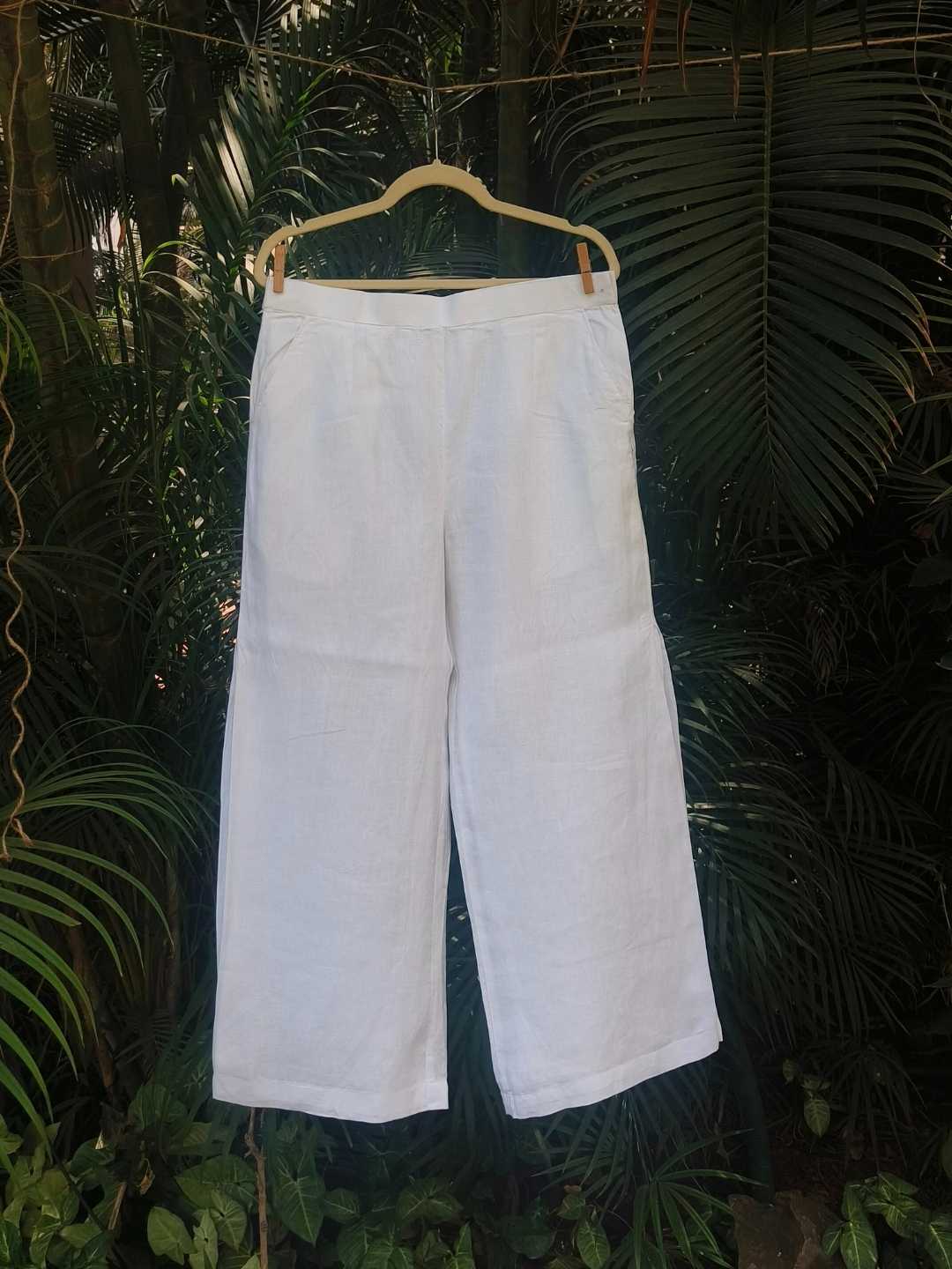 Vianca Pants- 100% Hemp | Jhultaru. Fabric: 100% Hemp Color: Classic White. Side seam pleat detail. Wide-leg silhouette. Mid-rise with back elastic. Pockets on both sides. Breathable, lightweight, eco-friendly and sustainable- Vianca Pants in 100% hemp with wide legs and soft pleats at the side seams. Clean, breathable, and made for slow, intentional living.