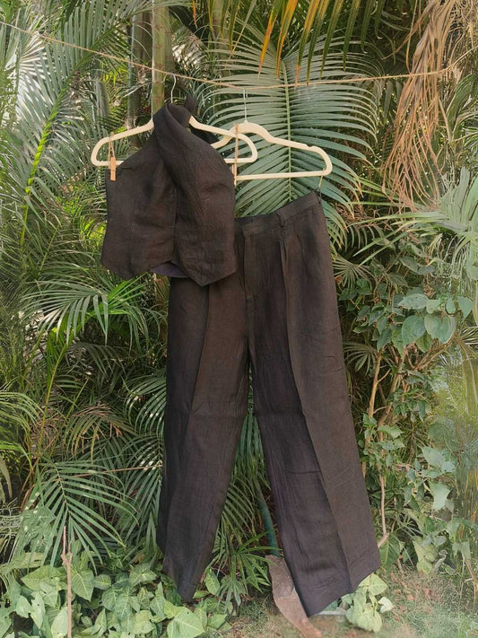 Noir Co-ord Set- 100% Linen Halter Vest & High-Waist Trousers in Charcoal Black | Jhultaru. Fabric: 100% Linen  Top: Halter Vest with structured neckline. Front closure: Hidden hook-eye  Bottom: High-waist wide-leg trouser with side zip & inner button- Noir Co-ord Set in 100% linen- featuring a halter vest and high-waist pants in charcoal. Sculpted silhouettes in sustainable, eco-friendly and breathable fabric for bold, soft dressing.