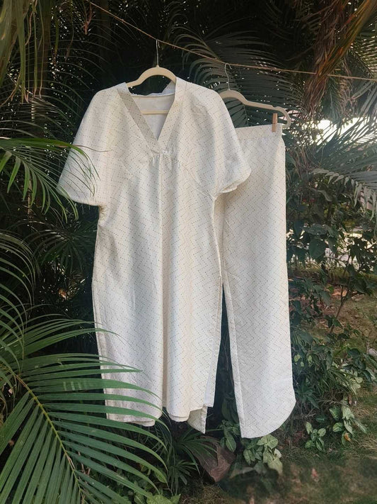 Selene Co-ord Set- Handwoven Kosa Silk | Jhultaru. Fabric: 100% Handwoven Kosa Silk  Color: Ivory White with golden zigzag weave  Kurta: V-neck, relaxed fit, soft gathers under bust  Pants: Straight fit with curved hem slits, high-waisted, full length- Selene Co-ord Set in handwoven kosa silk with golden zigzag weave. Includes V-neck kurta and curved-hem pants. Designed for fluid comfort and subtle elegance.