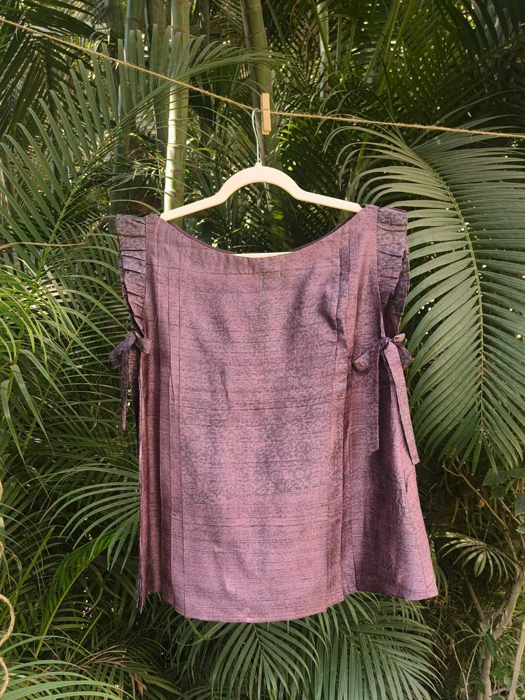 Velora Top- Handwoven Silk | Jhultaru. Fabric: 100% Handwoven Silk  Color: Deep Plum with Natural Irregularities. Pleated shoulder details. Side tie-ups for adjustable comfort. Relaxed, free-flowing silhouette. Soft sheen and breathable texture- The Velora Top in handwoven silk features pleated shoulders and side tie-ups, crafted in a rich plum tone with a soft sheen. Designed for comfort and elegance.