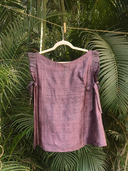 Velora Top- Handwoven Silk | Jhultaru. Fabric: 100% Handwoven Silk  Color: Deep Plum with Natural Irregularities. Pleated shoulder details. Side tie-ups for adjustable comfort. Relaxed, free-flowing silhouette. Soft sheen and breathable texture- The Velora Top in handwoven silk features pleated shoulders and side tie-ups, crafted in a rich plum tone with a soft sheen. Designed for comfort and elegance.