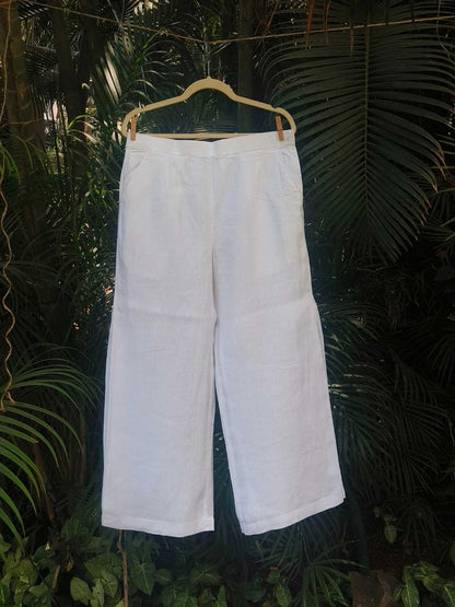 Vianca Pants- 100% Hemp | Jhultaru. Fabric: 100% Hemp  Color: Classic White. Side seam pleat detail. Wide-leg silhouette. Mid-rise with back elastic. Pockets on both sides. Breathable, lightweight, eco-friendly and sustainable- Vianca Pants in 100% hemp with wide legs and soft pleats at the side seams. Clean, breathable, and made for slow, intentional living.