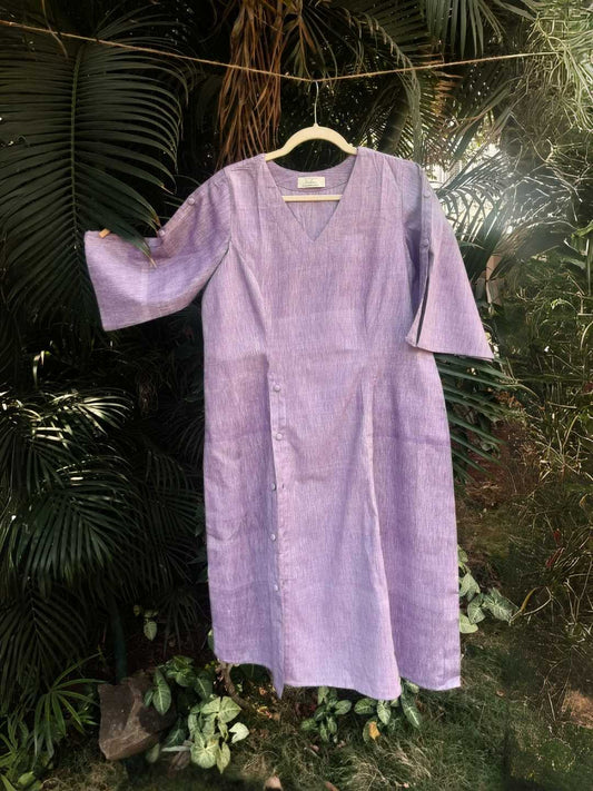 Voila Kurta- Handwoven Khadi Cotton | Jhultaru. Fabric: Handwoven Khadi Cotton  Color: LavenderV-neck with princess seam detailing. Three-quarter sleeves with button tab accents. Side button placket. Midi length with a soft flare. Lightweight and breathable- Voila Kurta in lavender khadi cotton with a V-neckline and side button placket. Eco-Friendly & Sustainable - made for the mindful wardrobe.